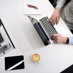 man on laptop with coffee on desk